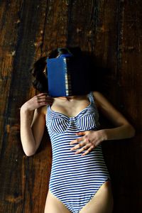 Midsection of woman holding camera while standing on wood