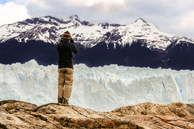 Rear view of person on snowcapped mountain against sky