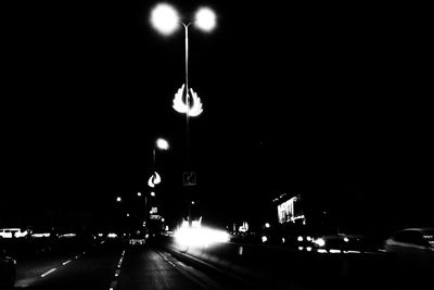 Illuminated street light on road at night