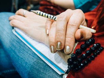 Midsection of woman holding pencil and book