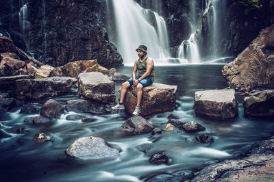 Young woman looking at waterfall in forest