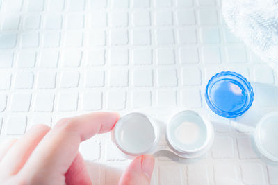 Midsection of person holding glass bottle on table
