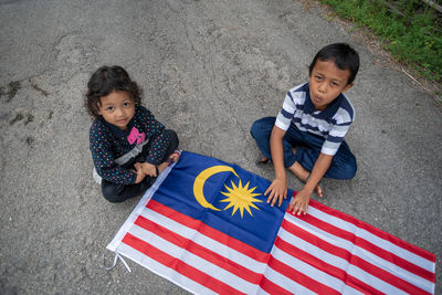 High angle portrait of friends playing with malaysian flag on road