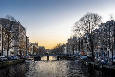 Canal amidst buildings against sky during sunset