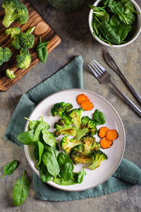 Grilled broccoli and carrots and fresh spinach leaves on a plate. vegetable diet. top and vertical 