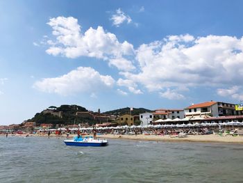 Nautical vessel at sea by buildings against sky