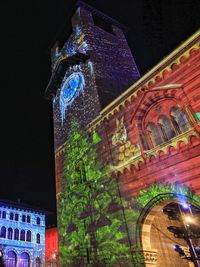 Low angle view of illuminated clock tower at night