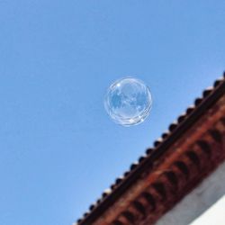 Low angle view of bubbles against blue sky