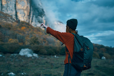 Rear view of woman standing on mountain against sky