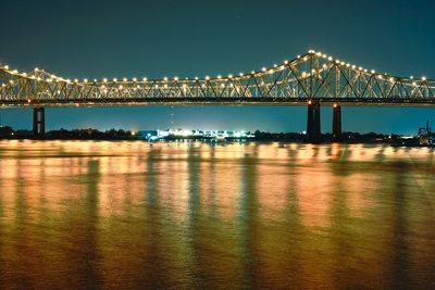 Illuminated bridge over river against sky at night