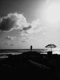 Silhouette man standing on beach against sky