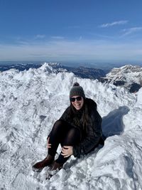 Woman sitting on snow covered landscape laughing 