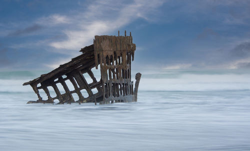 Wreck of the peter iredale in sea against sky