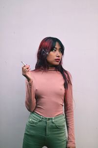 Beautiful young woman standing against wall