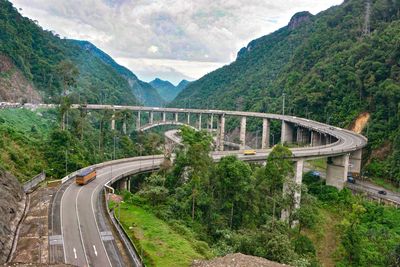 Road leading towards bridge against mountains