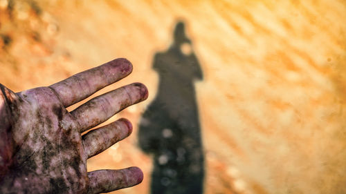 Cropped messy hand against shadow of person at desert