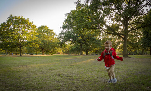 Full length of boy walking on grassy field in park