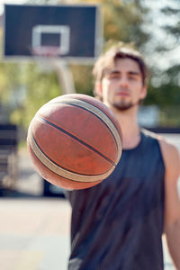 Portrait of young man showing basketball
