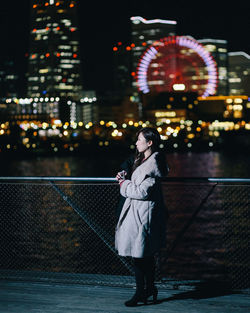 Woman standing against illuminated building at night