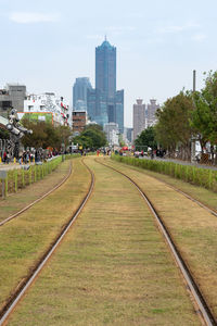 Railroad tracks by buildings in city against sky
