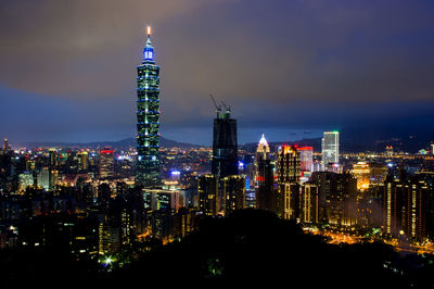 Taipei 101 amidst illuminated buildings in city at night