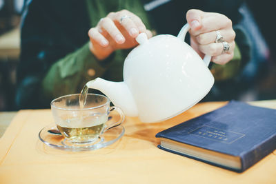 Close-up of woman holding coffee cup on table