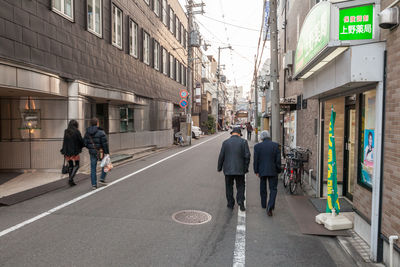 People walking on street amidst buildings in city