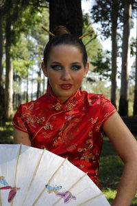 Portrait of smiling young woman standing against trees