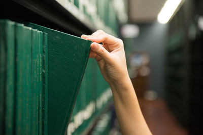 Close-up of hand removing book from shelf in library