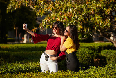 Woman with arms raised while standing against plants