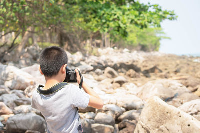Rear view of man photographing on rock