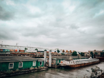 Buildings by river against sky in city