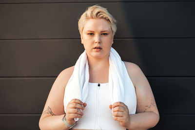 Portrait of beautiful young woman standing against wall