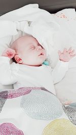 High angle view of cute newborn baby sleeping on bed at home