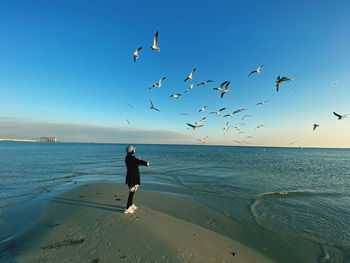 Rear view of woman flying over beach against sky