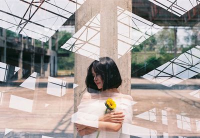 Double exposure of buildings and woman holding sunflower