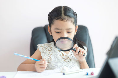 Portrait of a girl wearing sunglasses while sitting against wall