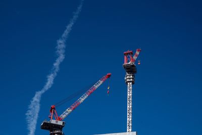 Low angle view of crane against clear blue sky