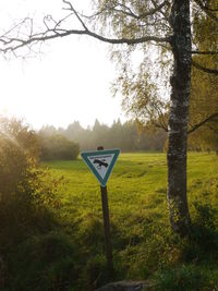 Information sign on field against sky