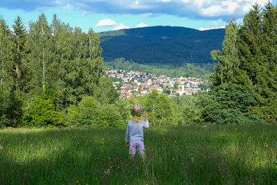 Rear view of woman standing on field against sky