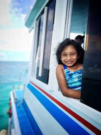 Portrait of girl looking through window while travelling in boat on sea