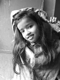 Portrait of girl smiling while standing against wall