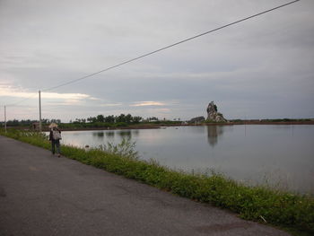 Rear view of man walking on road against sky