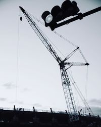 Low angle view of silhouette cranes against sky
