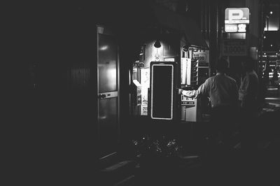 Rear view of man standing in illuminated room
