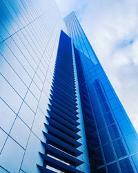 Low angle view of modern glass building against sky