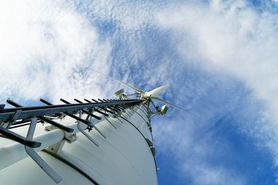 Wind turbine from a deep angle, view along the mast to the rotor blades, above blue sky with clouds