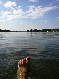 Low section of person in lake against sky