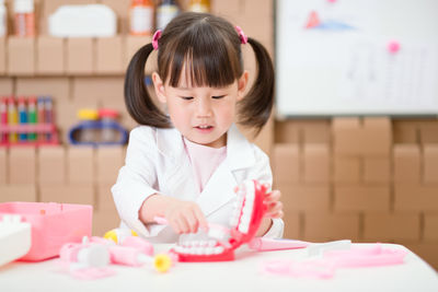 Young girl pretend play dentist role at home