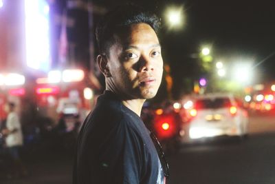 Portrait of man against illuminated city at night